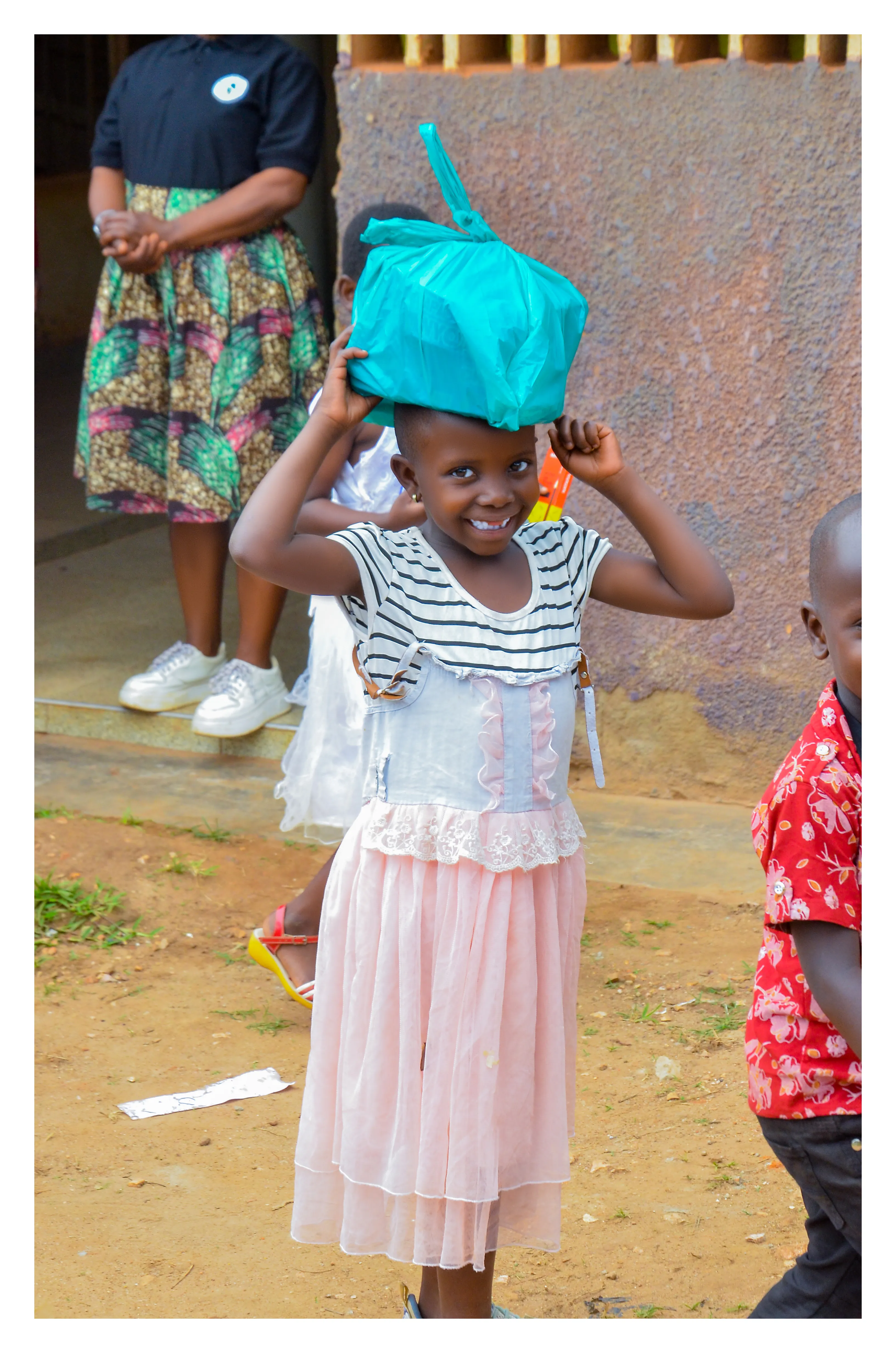 A smiling child carrying a food parcel from the foundation